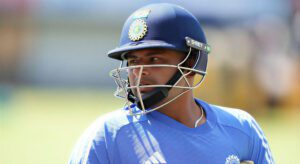 Cricket player wearing helmet and pads during a match, focused on the game.
