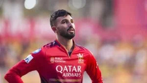 Cricket player wearing red jersey during match, focused on the game.